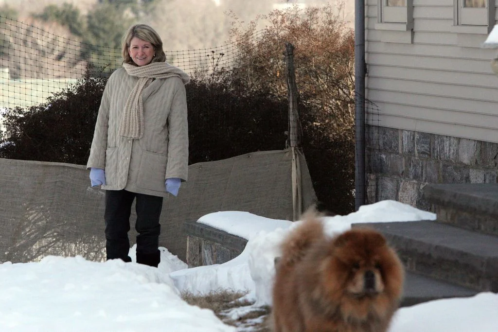 Martha Stewart in beige jacket and scar in background standing outside on the snowy grounds of her upstate New York home...