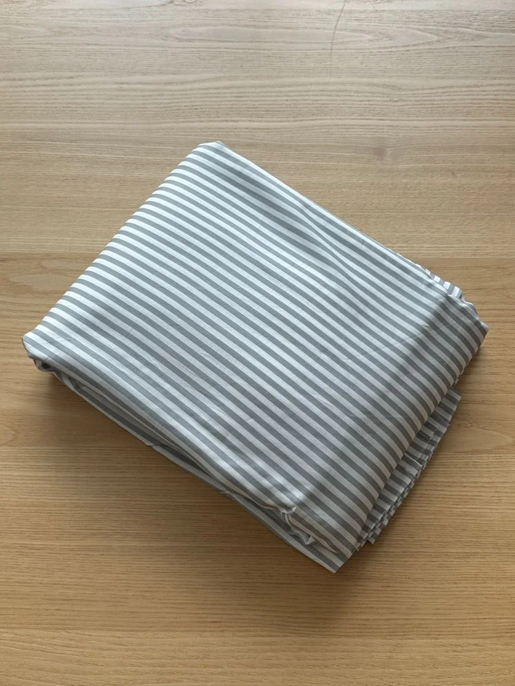 Striped sheets folded on a wooden table.