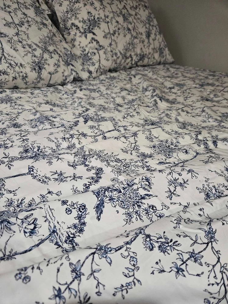 Toile print sheets on a bed.