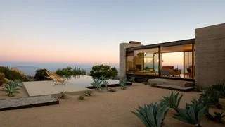 Exterior of a modern home with desert landscape overlooking the ocean.