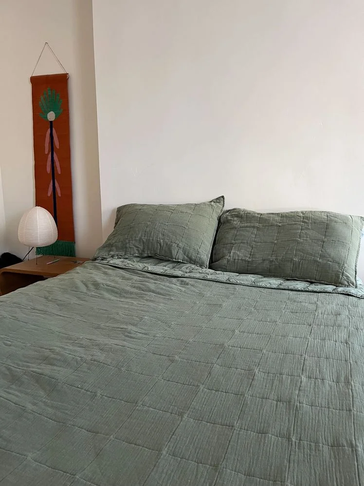 Bed made with a green Cotton Gauze Quilt.