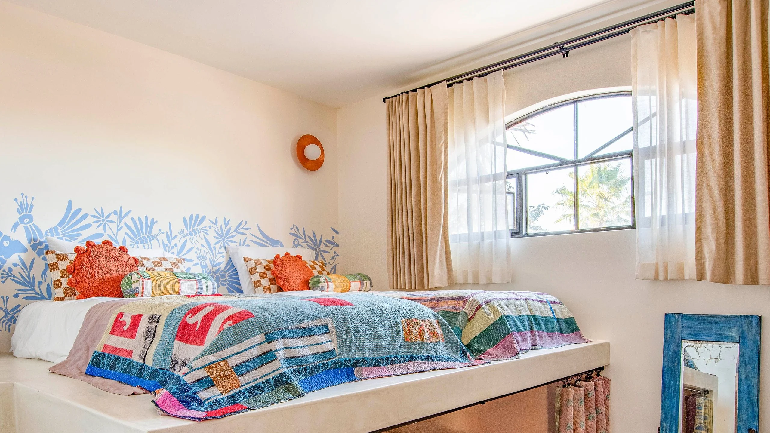 Children's room with two beds on a mezzanine and one bed underneath all dressed with colorful quilts.