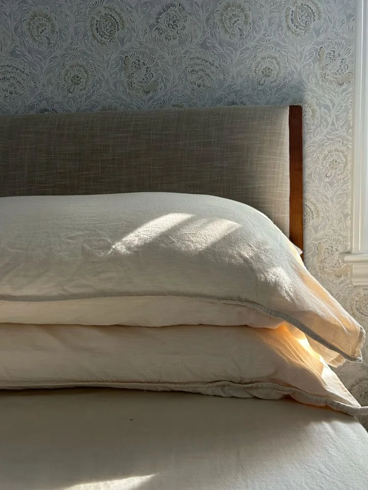 Bed with two pillows stacked in front of the headboard.