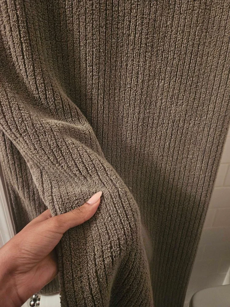 Person's hand holding a gray bath towel.