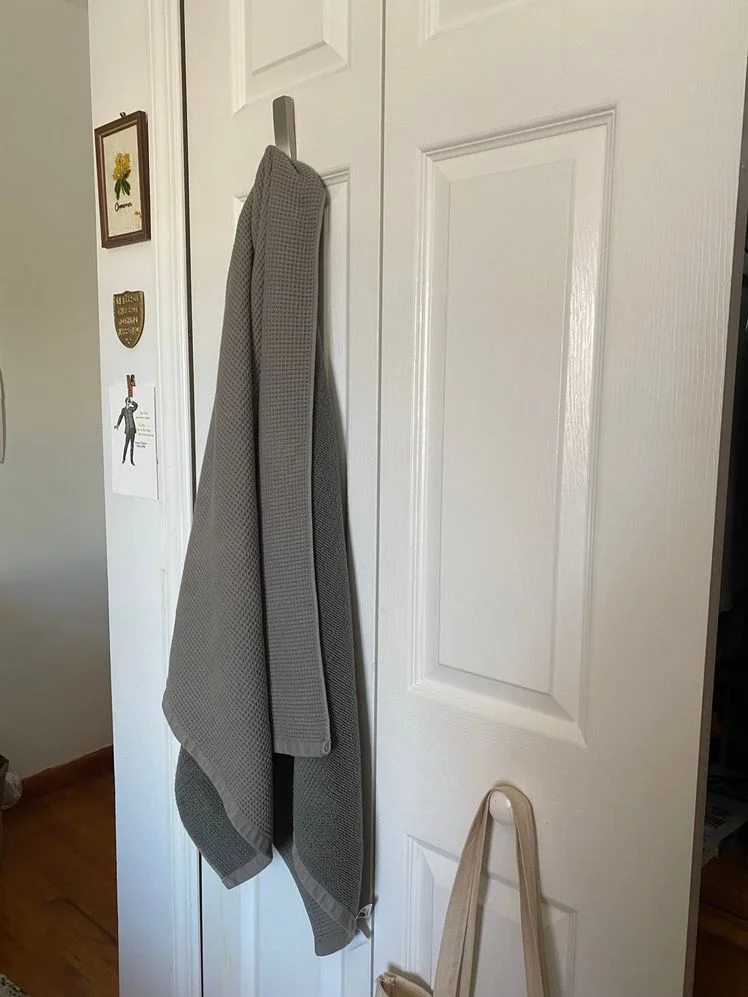Gray waffle towel hanging from a hook on a door.