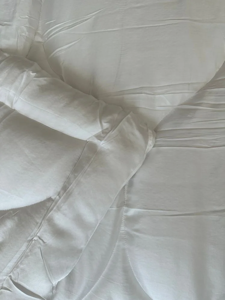 Corner of a white comforter with patterned stitching on it.