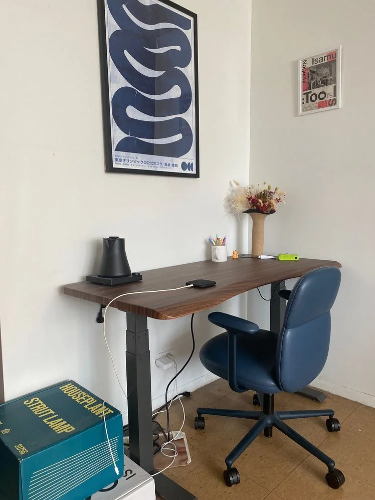 Blue desk chair at a wood desk with artwork over it.