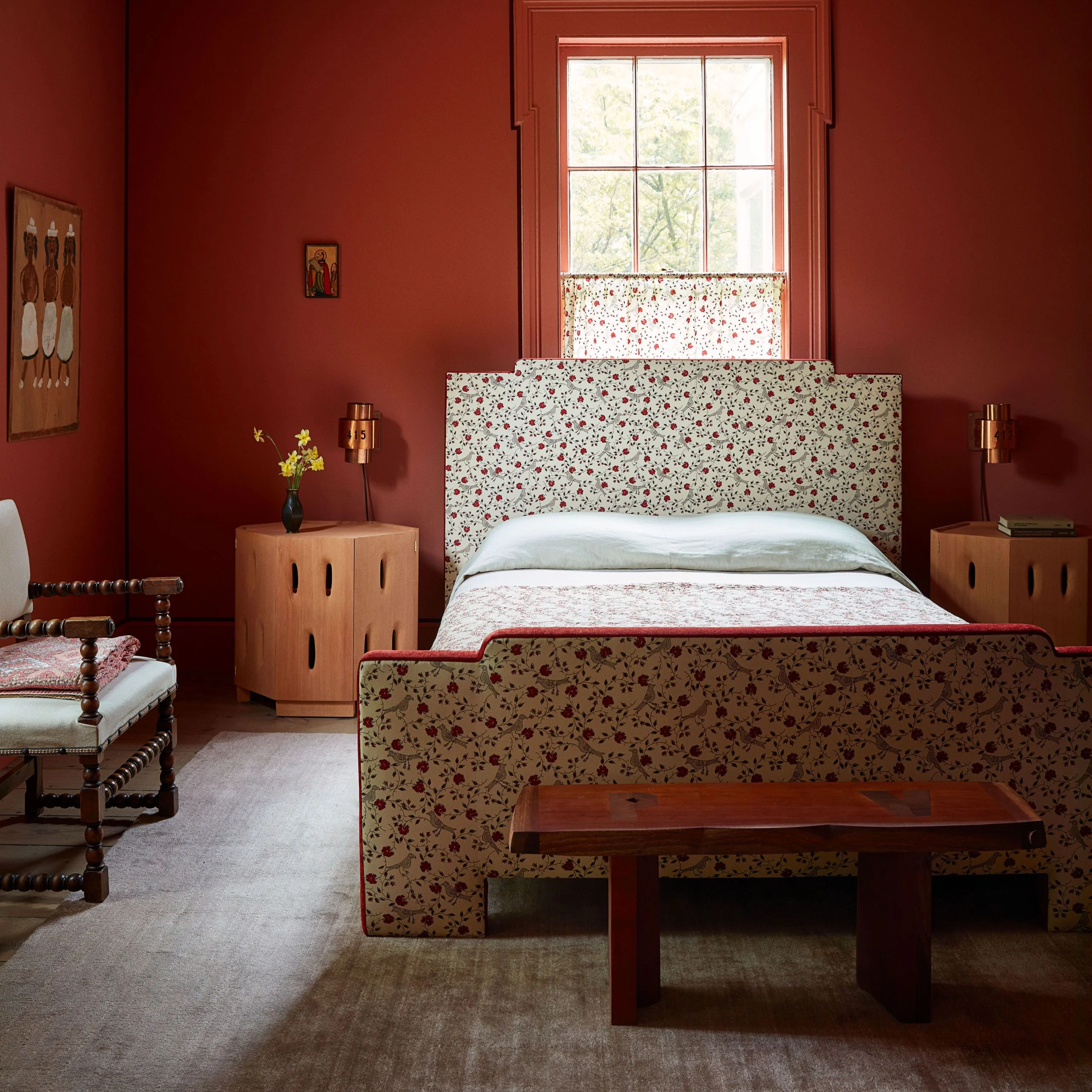 Bedroom with upholstered bed frame in floral fabric and wood bench at the end.