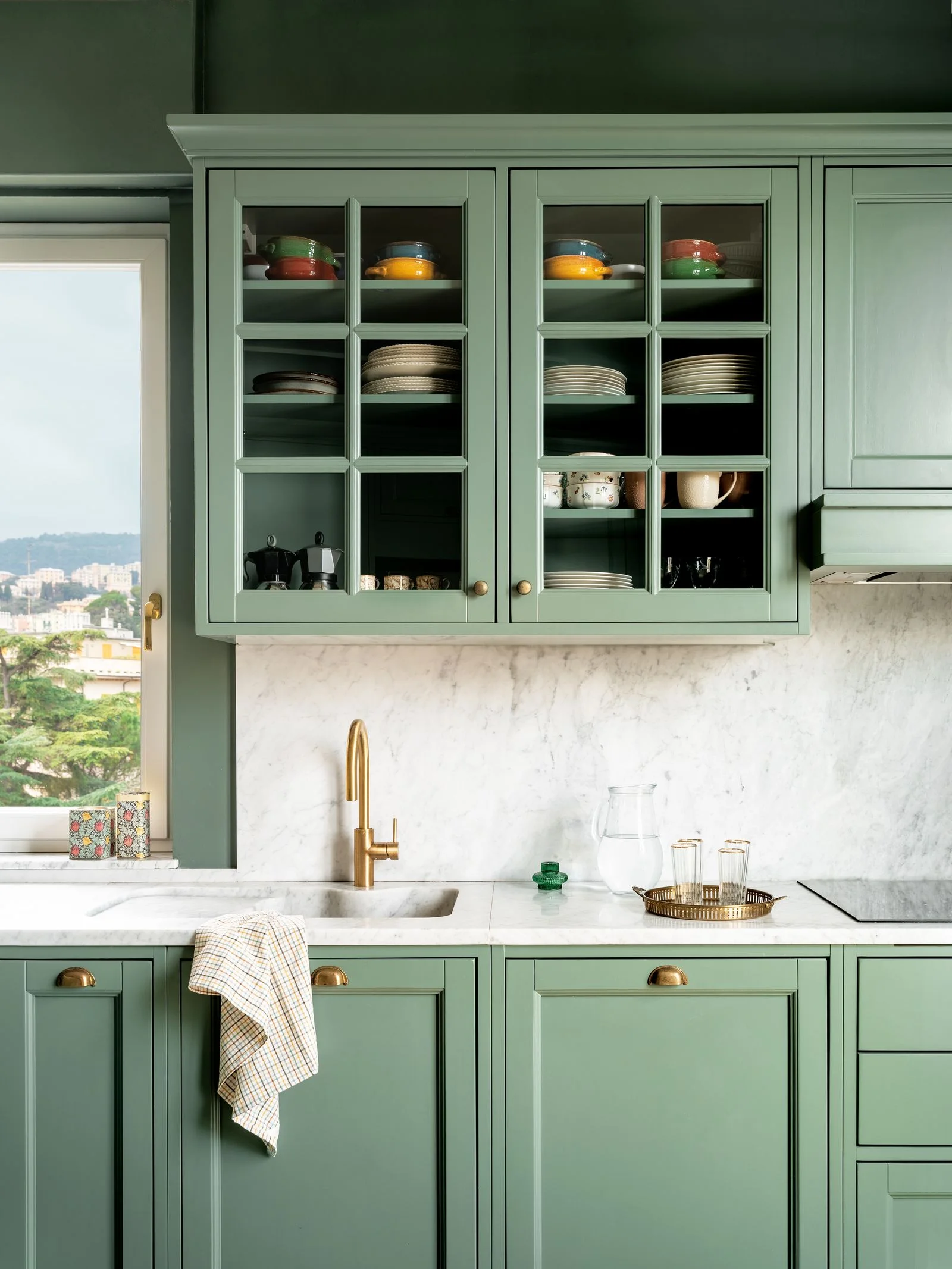 cucina verde salvia piano e paraschizzi in marmo pensili con ante in vetro stoviglie