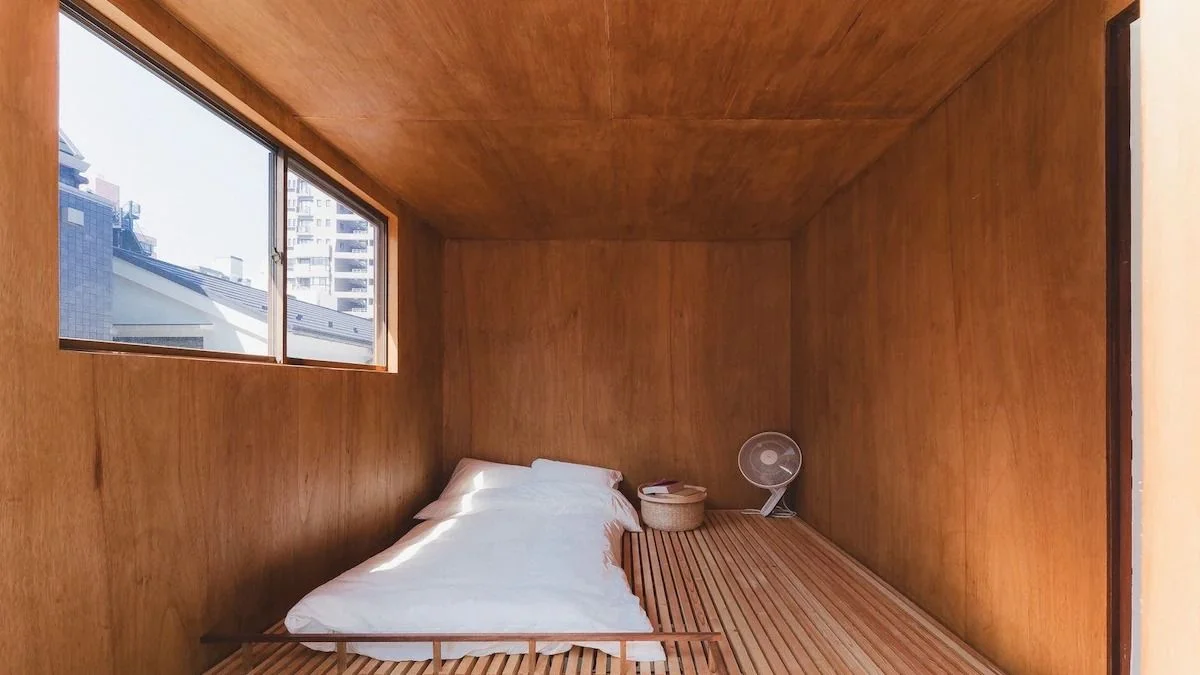 A loft area features wood panel walls a window and a futon.