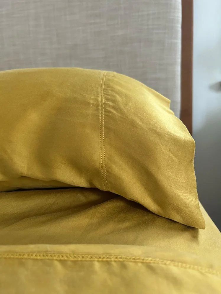 Closeup of a made with a yellow fitted sheet and matching pillowcase.