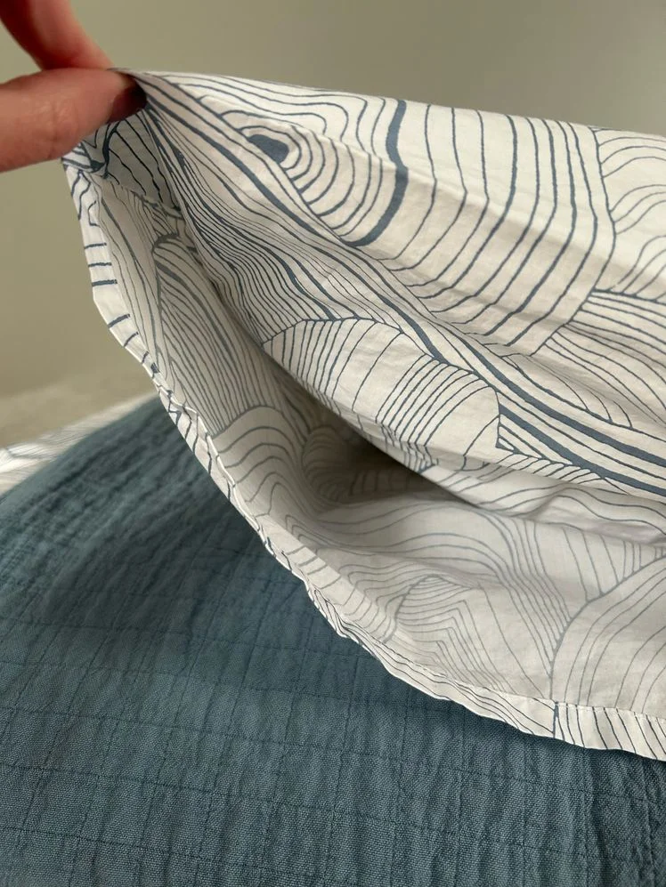 Person holding the edge of a patterned pillowcase.