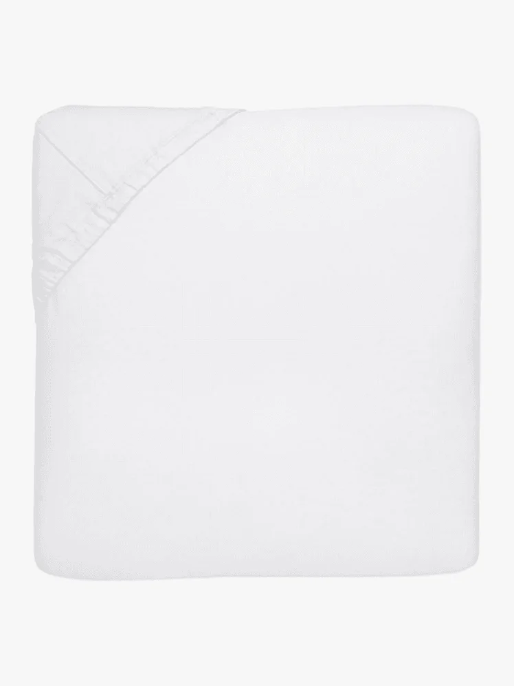 A white fitted sheet over the corner of a white mattress