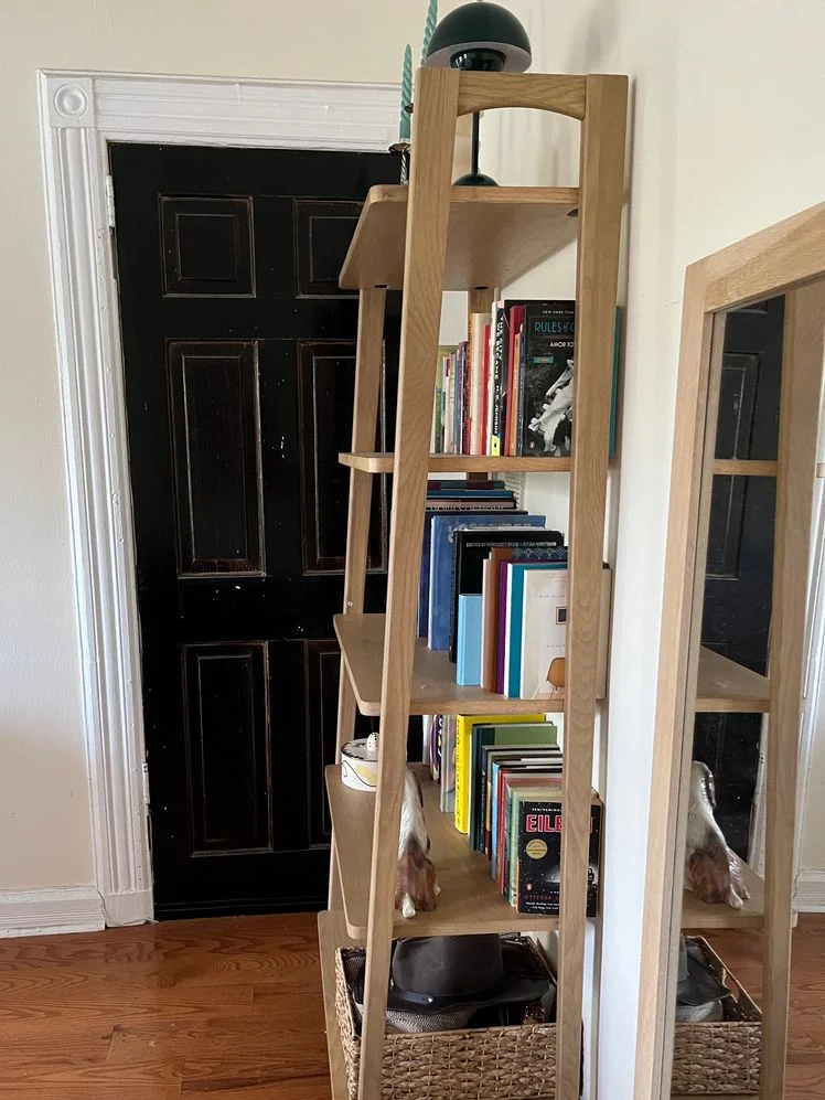 5-tier wooden bookshelf styled with assorted books, candles, sculptures, and art shown from the side.