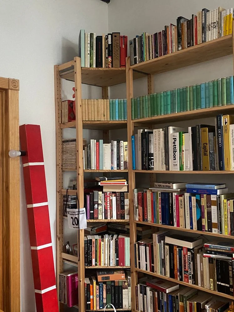 Pine wood bookshelf stuffed with books in a living room.