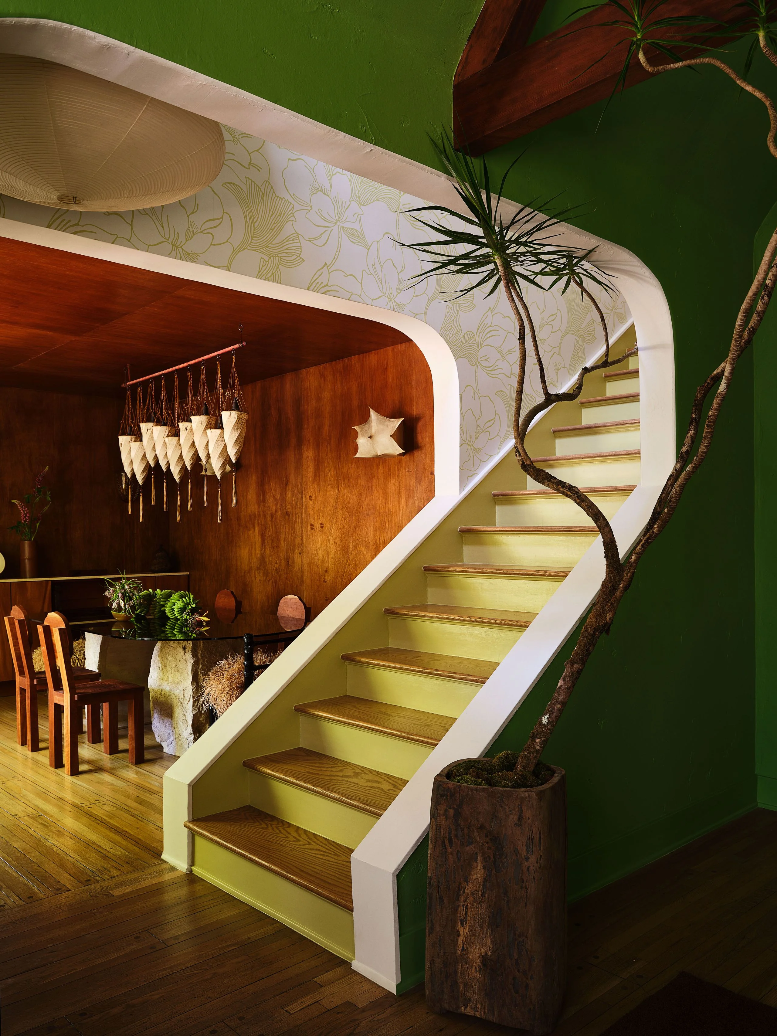 Staircase with chartreuse fronts next to a dining room with wood paneled walls.