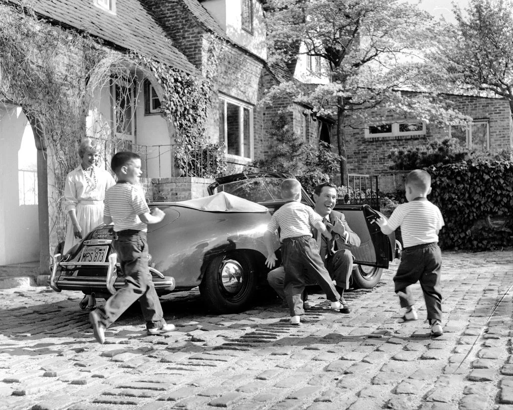 blackandwhite photo of Johnny Carsons wife and kids greeting him in driveway of New York home