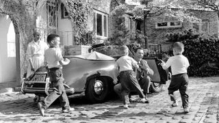 blackandwhite photo of Johnny Carsons wife and kids greeting him in driveway of New York home