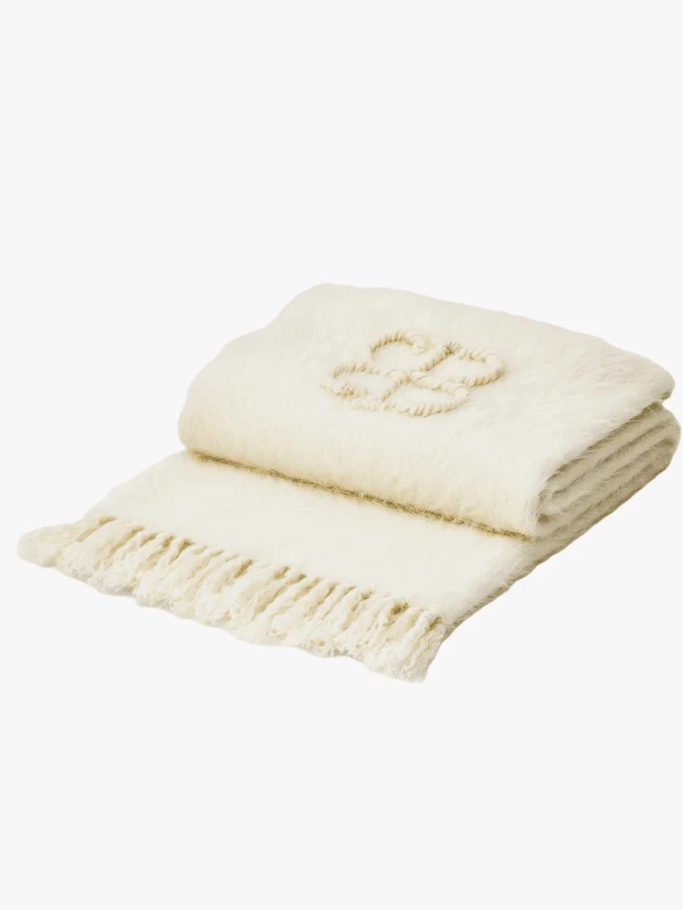 A white throw blanket with fringe edges 