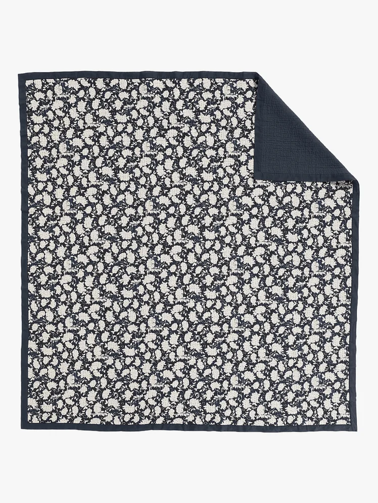 A black quilt with a white floral design