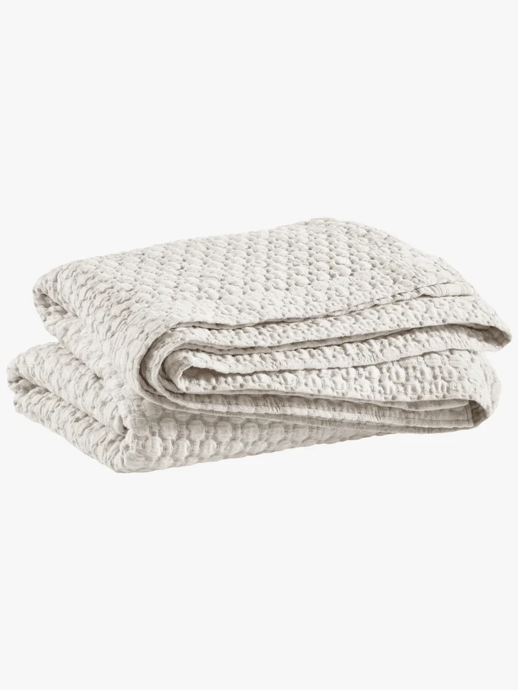 A white quilted coverlet folded up 