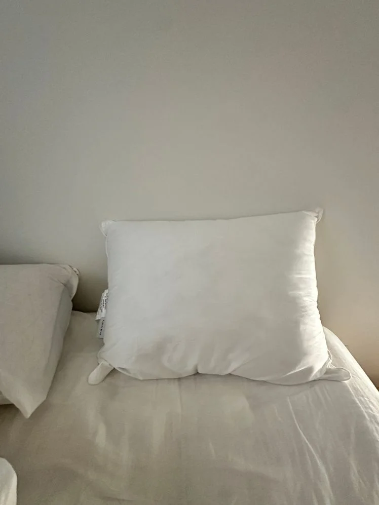 Down alternative pillow resting on a bed.