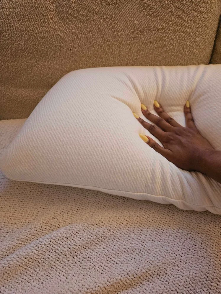 Person's hand pressing down on a pillow.