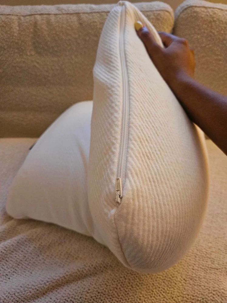 Person's hand holding up a pillow to show the side zipper.