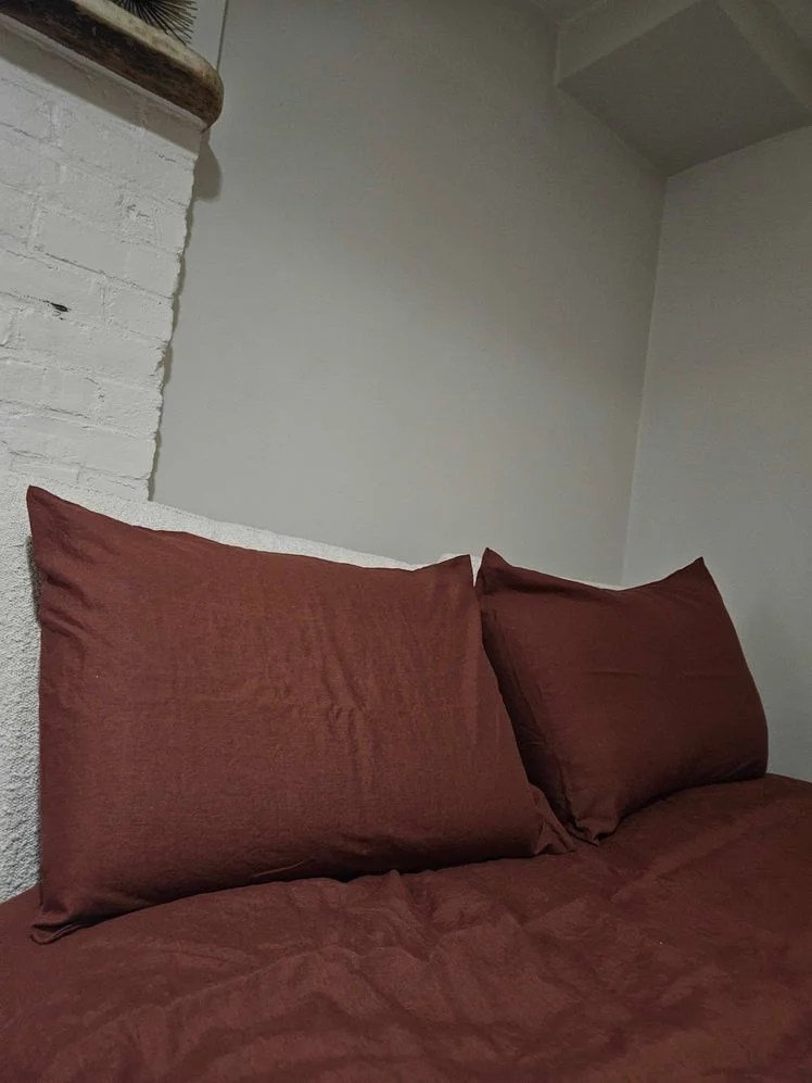 Bed made with rust-colored sheets and matching pillowcases.
