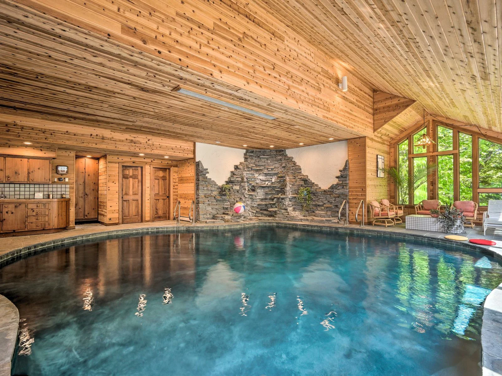 Indoor pool inside a room with a woodpaneled ceiling.