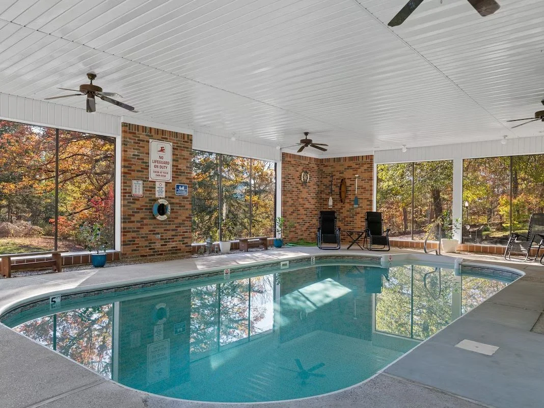 A pool with brick walls and large windows also features ceiling fans and lounge chairs.