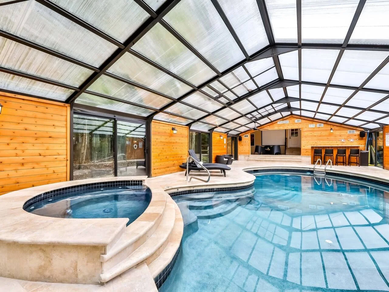 Indoor pool and jacuzzi in a room with a vaulted ceiling of skylights at an Airbnb in Tobyhanna Pennsylvania.