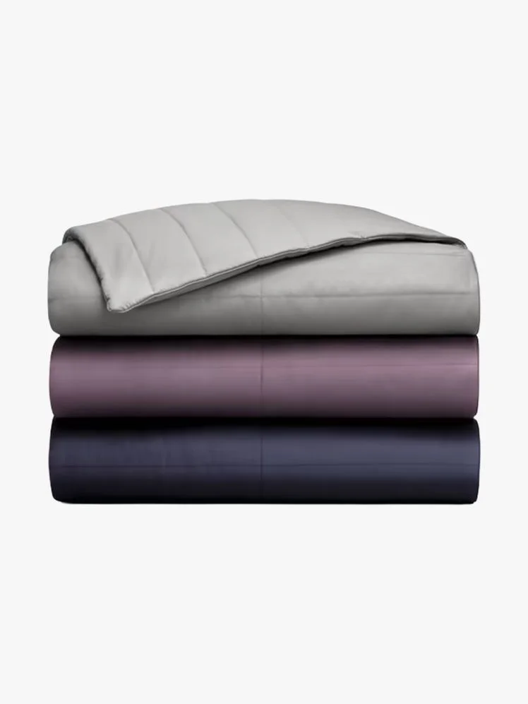 Stack of three blankets in navy, purple, and gray.