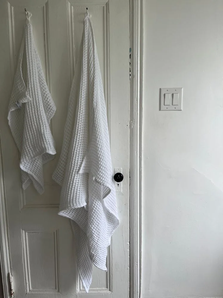Two white waffle weave towels hanging on the back of the bathroom door.