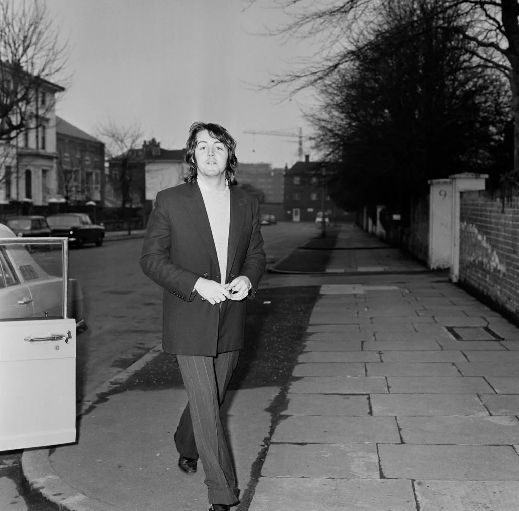 blackandwhite photo of Paul McCartney walking on sidewalk outside his St Johns Wood house
