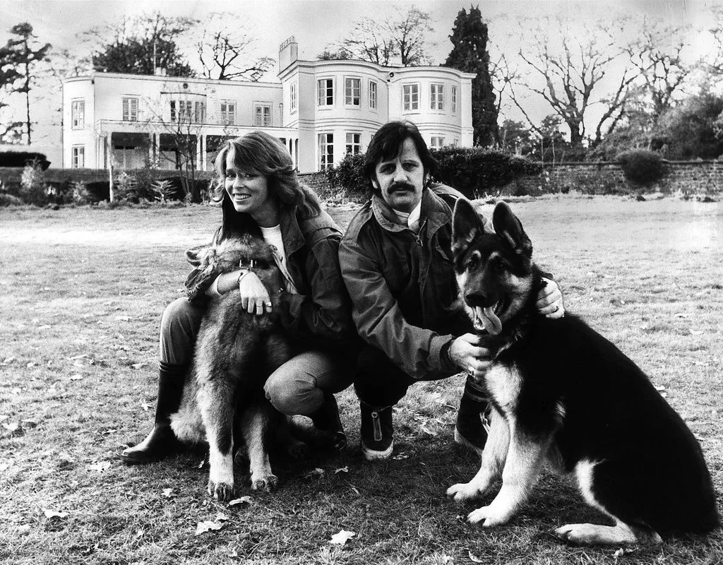 blackandwhite photo of Ringo Starr right with wife Barbara and their two dogs posed on the lawn of Tittenhurst estate