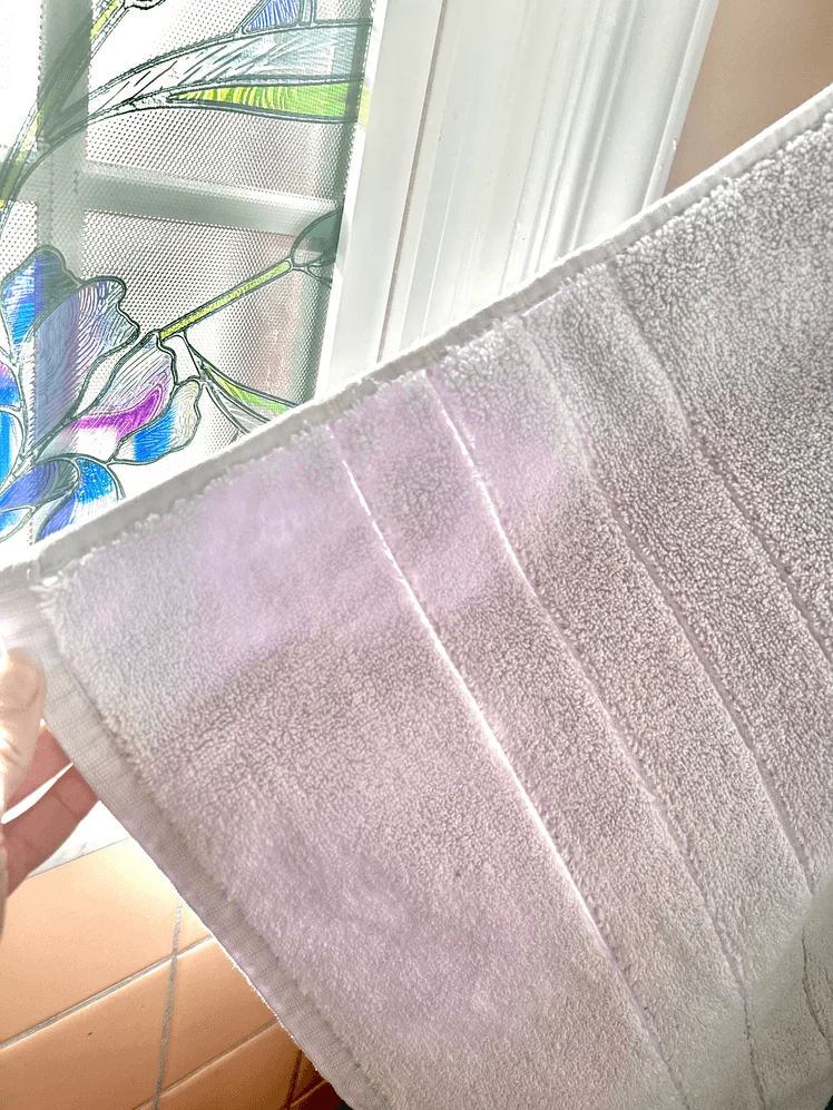 Person holding up the edge of a bath towel.