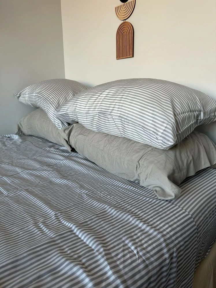 Bed with four pillows made with striped sheets.