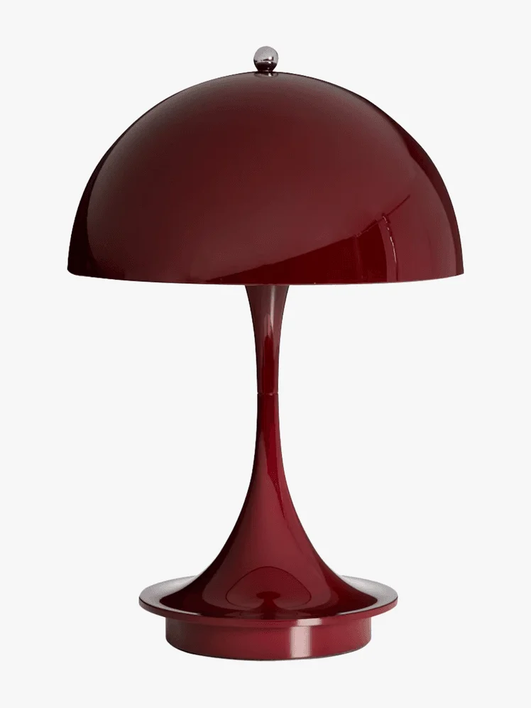 A glossy maroon table lamp with a dome-shaped shade and sleek, curved base set against a plain white background, conveying a modern, elegant feel.