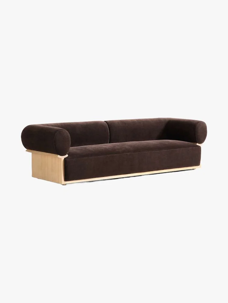 Couch with wood frame holding an oversized brown velvet upholstery.