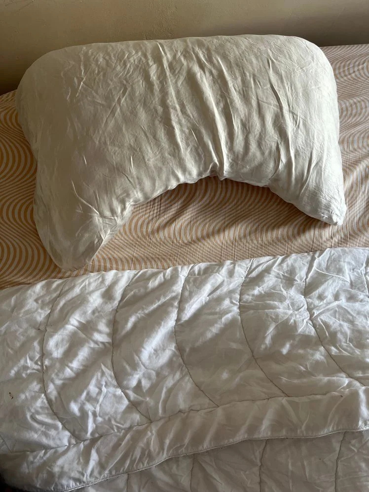 Pillow, quilt, and striped sheet on a bed.