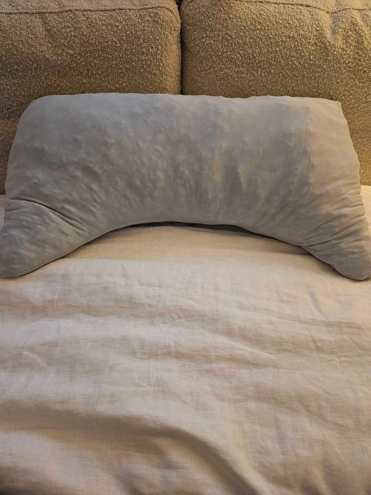 Crescent shaped pillow on bed.