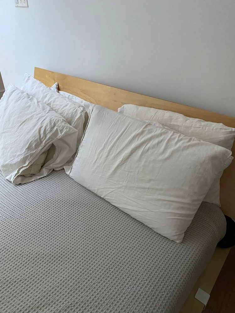 Bed made with four pillows, each in beige pillowcases.