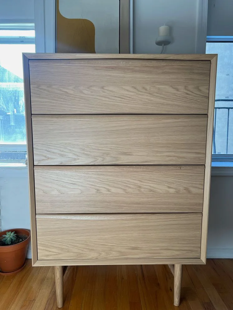 Wooden 4-drawer dresser in a bedroom.