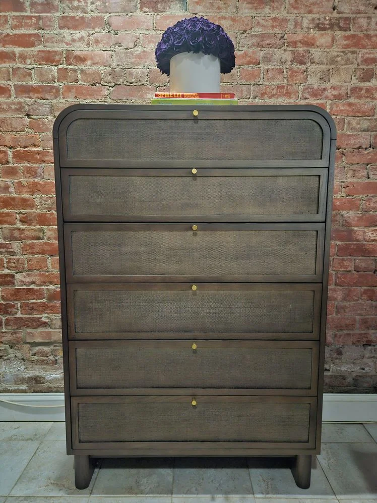 Brown wood dresser with gold hardware in front of a brick wall.