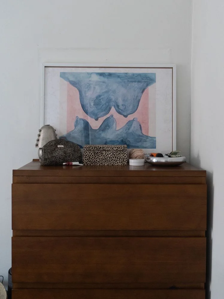 Thuma wood dresser with a framed art piece, lamp, and assorted toiletries on top of it.