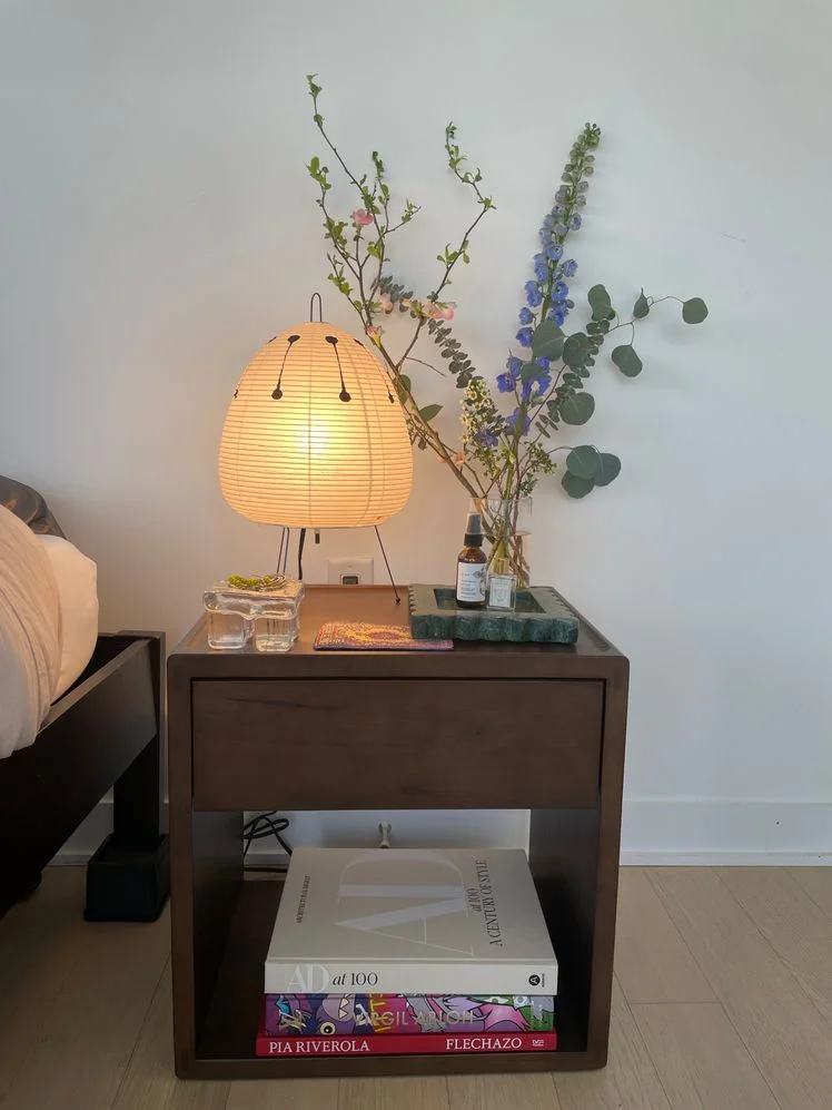 The Nightstand by Thuma styled with lamp, books, and small vase of purple flowers.