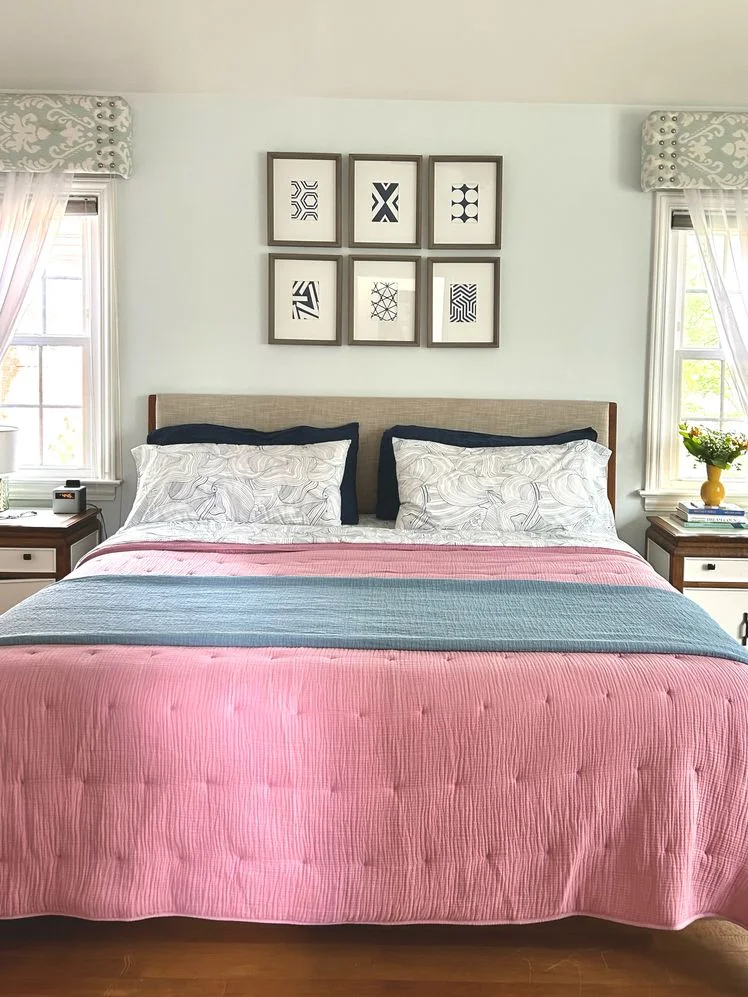 Bed made with a pink quilt and blue bed blanket.